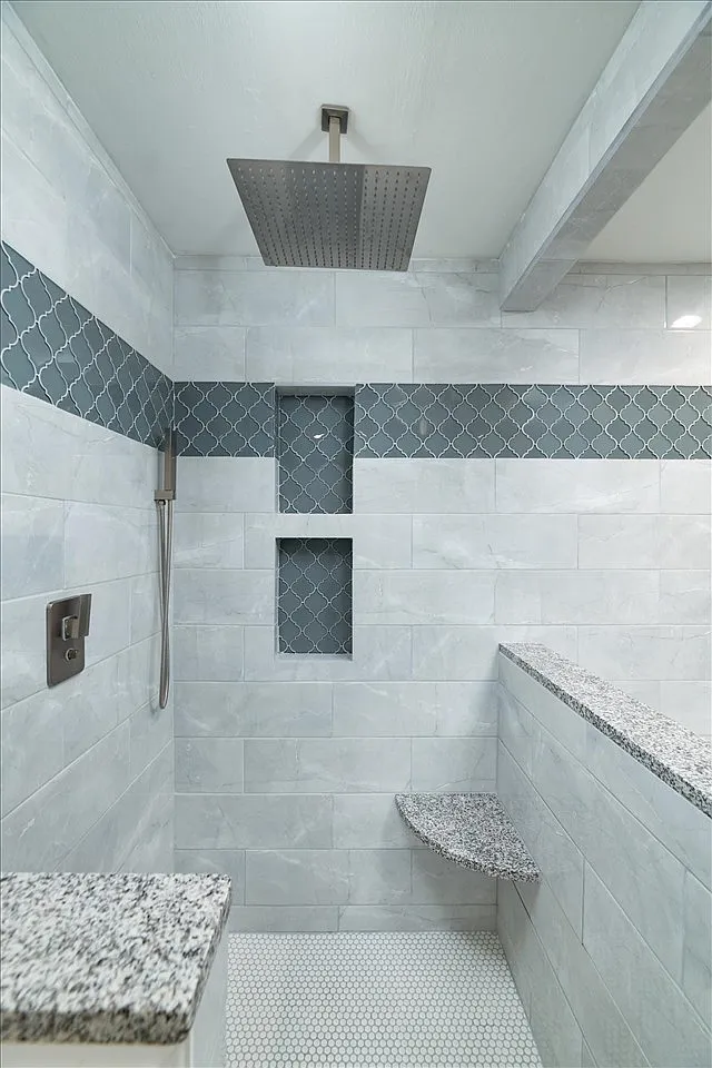 Walk-in shower with blue arabesque mosaic accent stripe, double niche, rain head, and granite bench